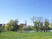 Der Blick über einen grünen Park mit See auf eine Kirche in Straubing.