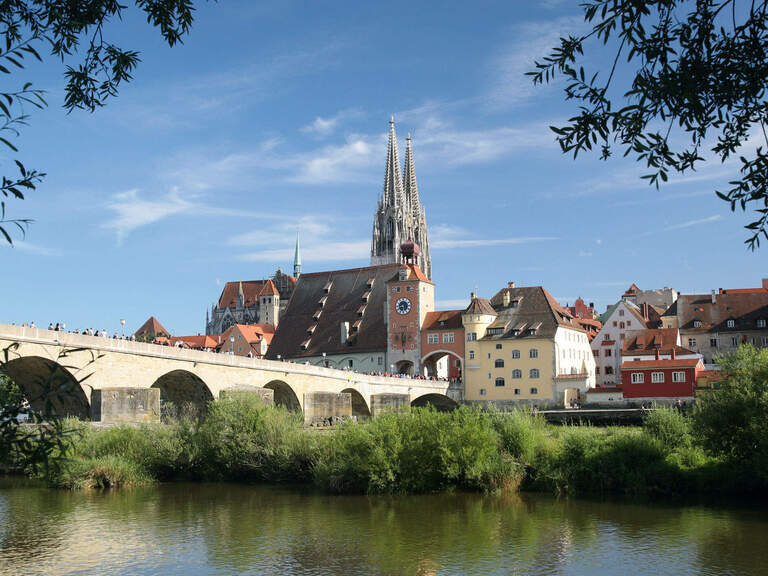 Eine malerische Steinbrücke überspannt den Fluss vor der Altstadt von Regensburg.