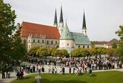 Eine Menschengruppe versammelt sich vor der eindrucksvollen Altöttinger Kirche, einem beliebten Wallfahrtsziel.